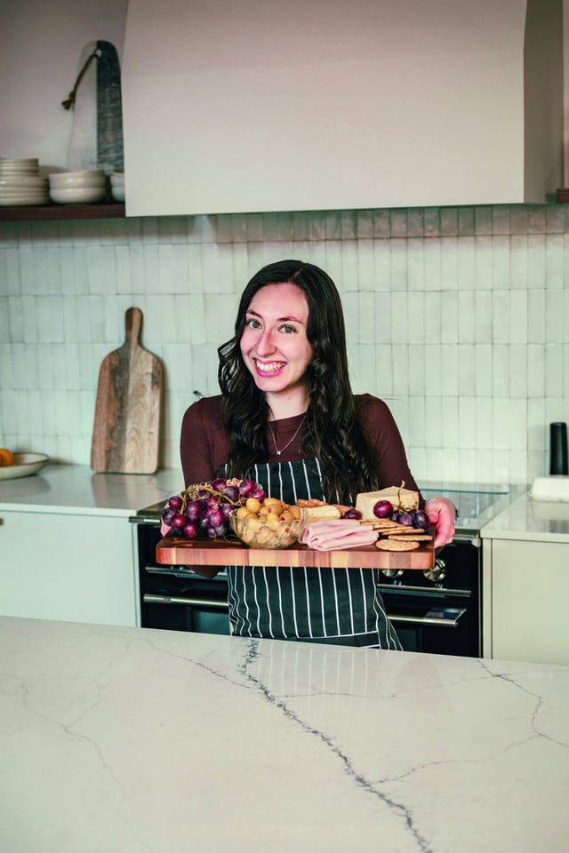Emilie tient une planche de charcuteries en tablier rayé
