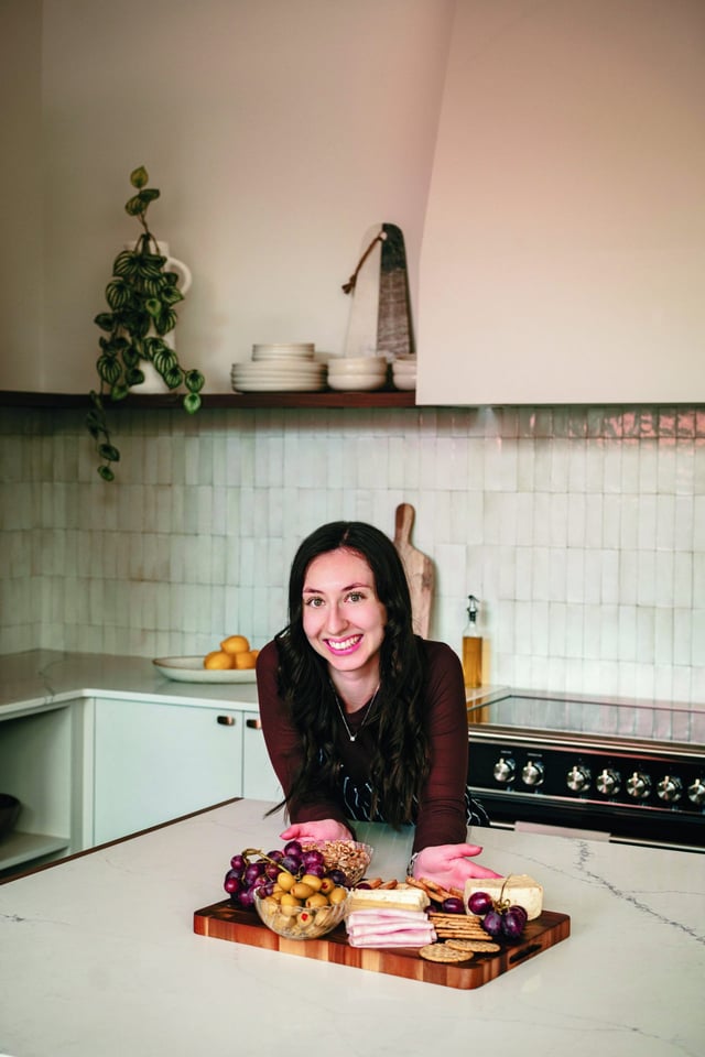 Emilie accoudée à l'îlot devant une planche de charcuteries